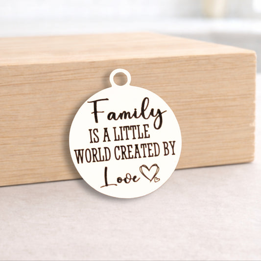 Round pendant with 'Family is a little world created by love' text on a wooden block.