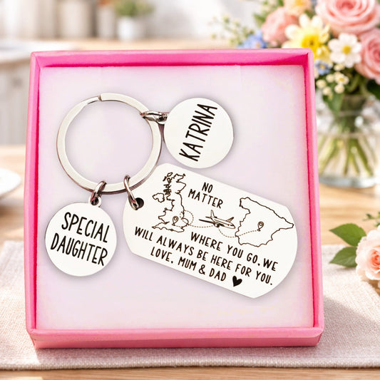 Keychain set with engraved message in a pink box on a table with flowers in the background