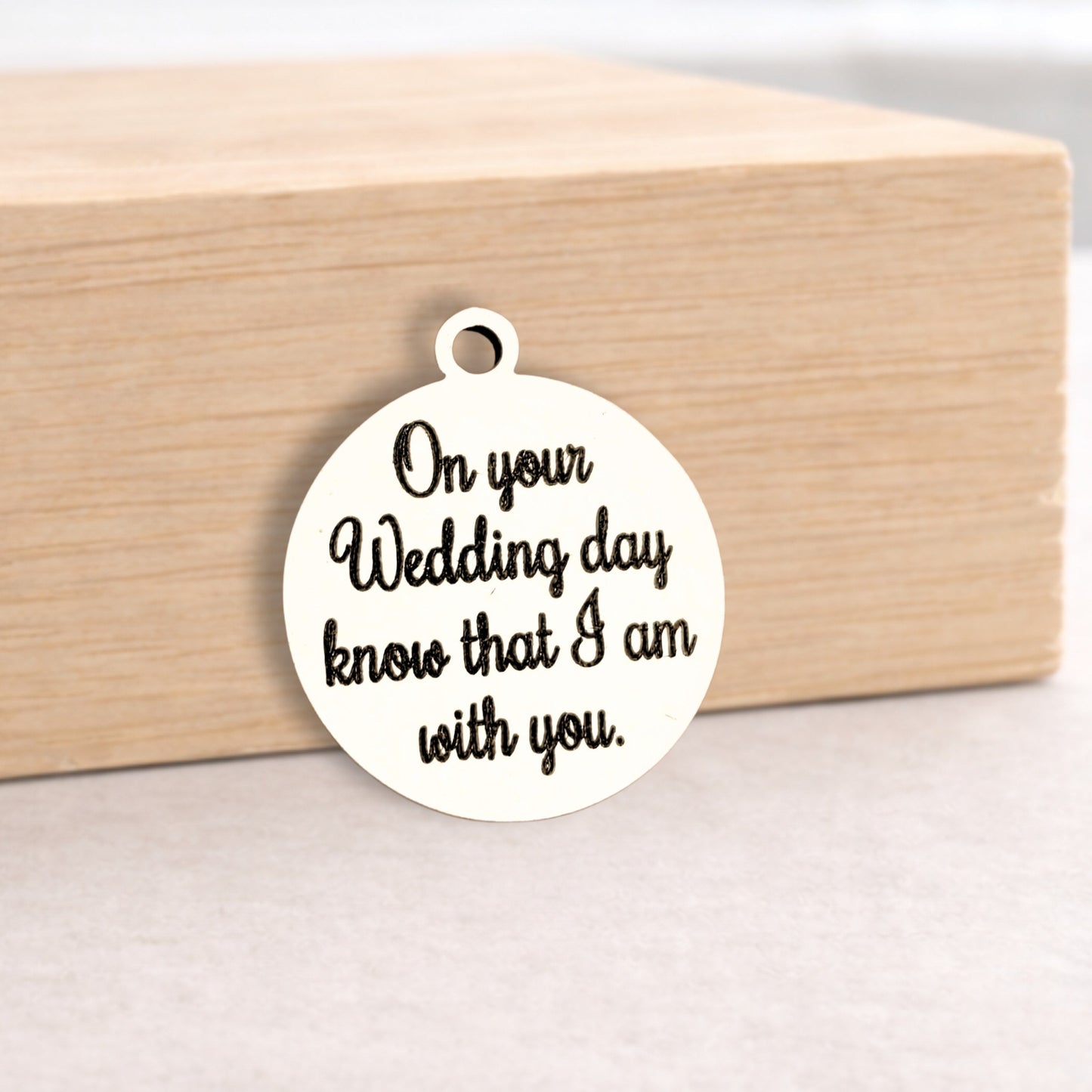 Round metal pendant with engraved text on a wooden block