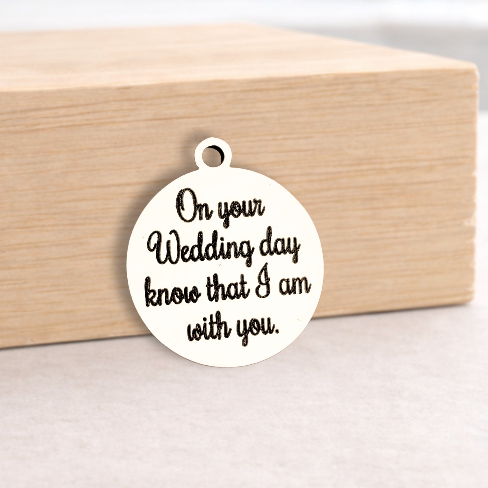 Round metal pendant with engraved text on a wooden block