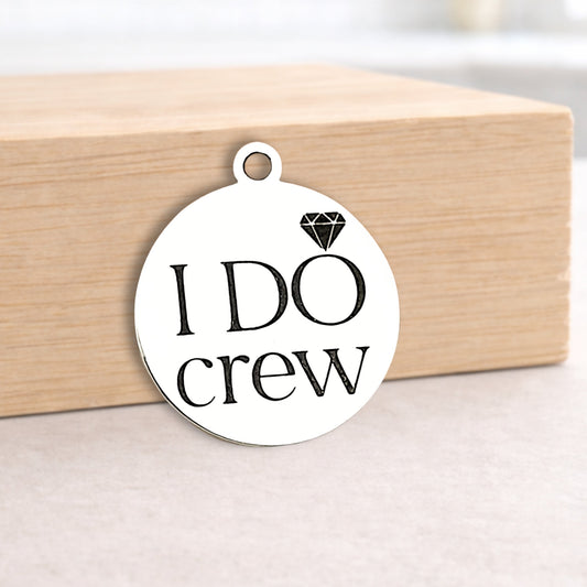 Round metal pendant with 'I DO crew' text on a wooden block