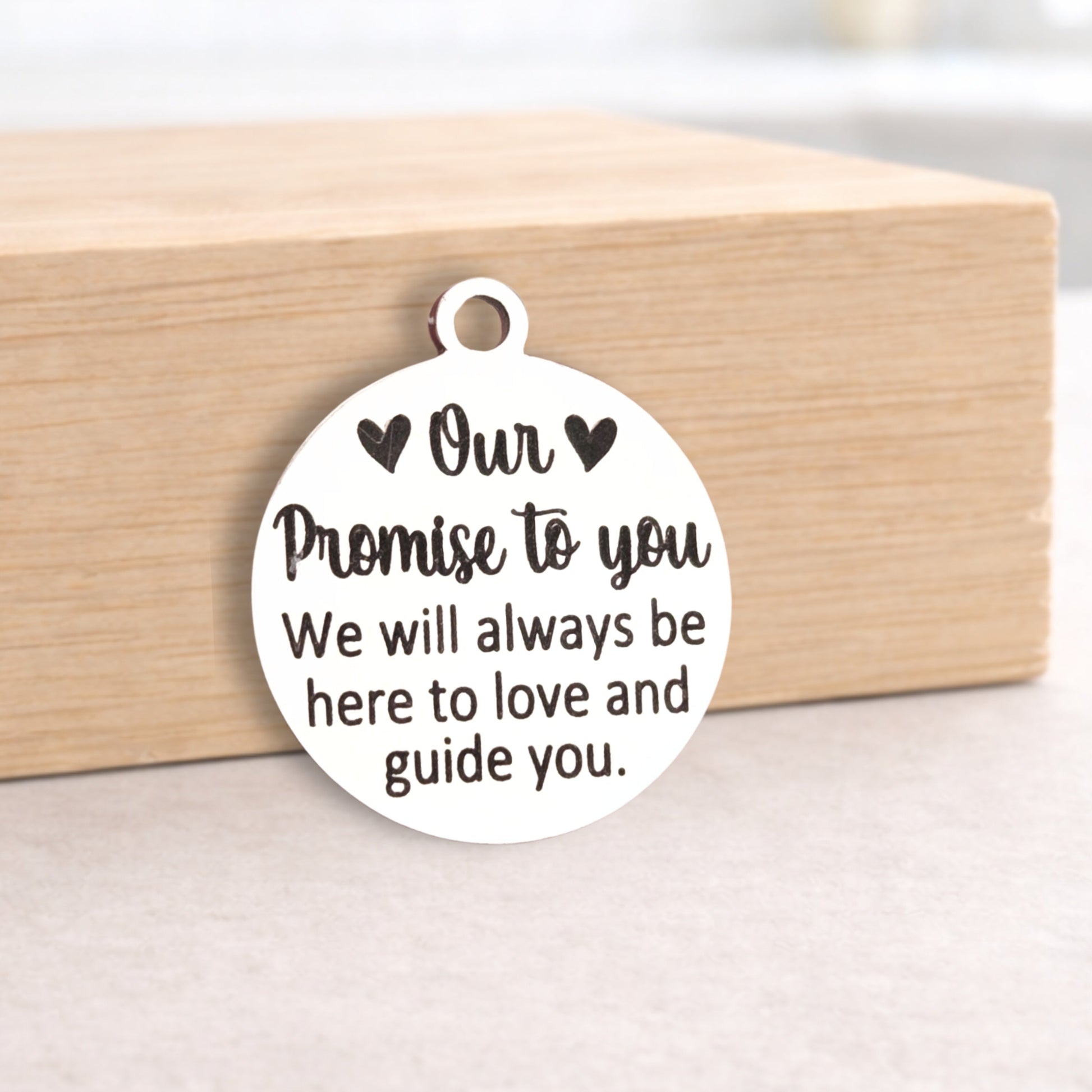 Round metal pendant with engraved message on a wooden block