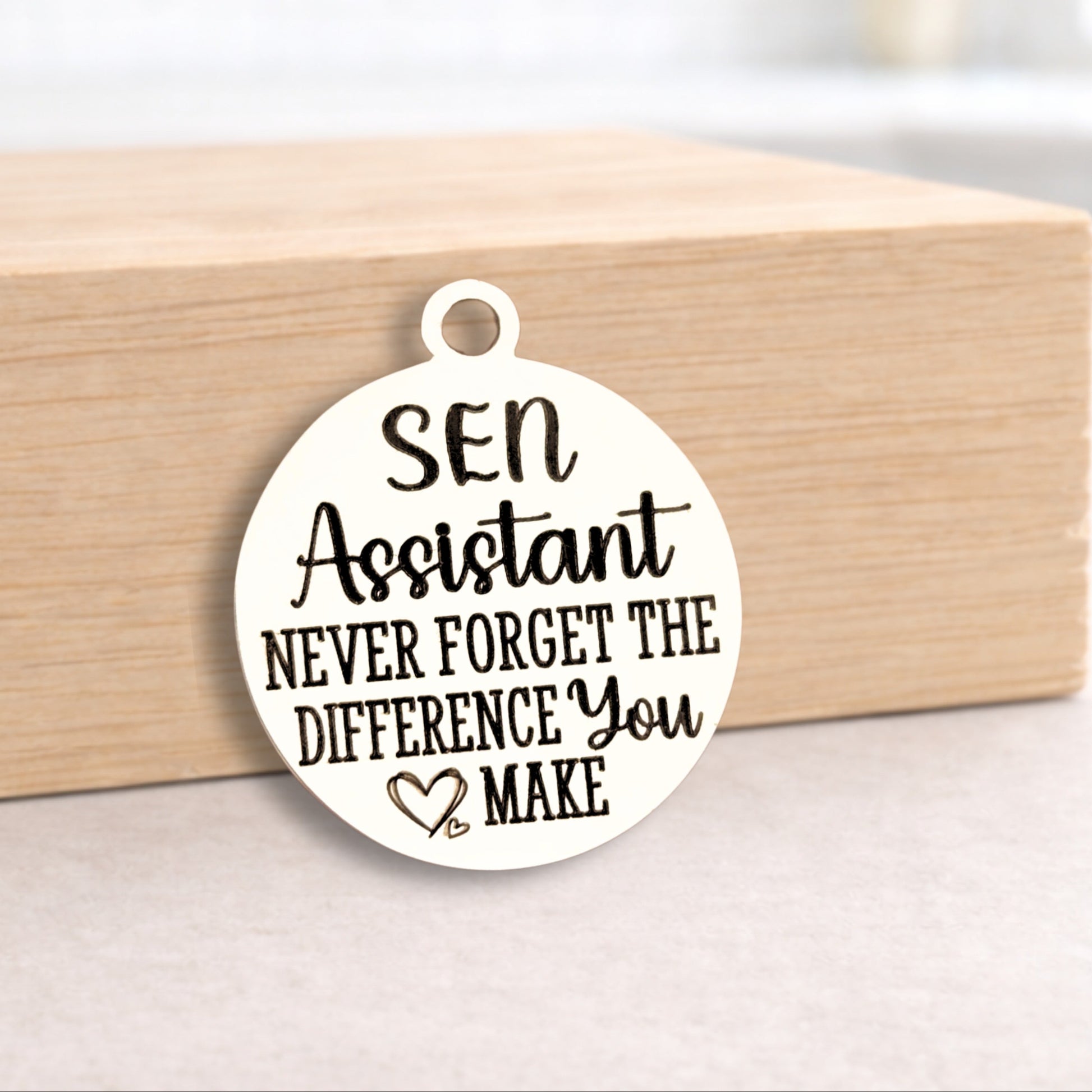 Round white pendant with text on a wooden block