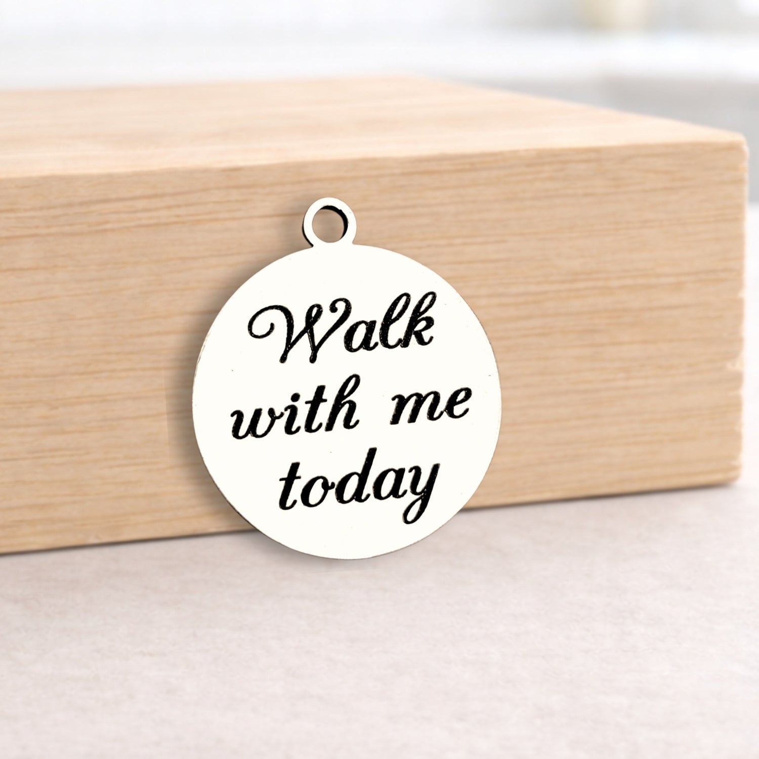 Round white pendant with 'Walk with me today' text on a wooden block.