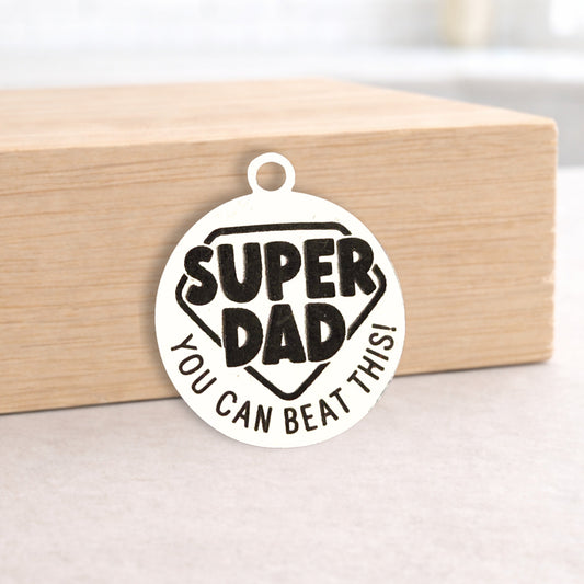 Circular pendant with 'Super Dad You Can Beat This!' text on a wooden block.
