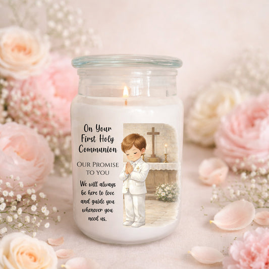 Candle in a jar with a printed design of a boy in a white robe and text, surrounded by pink flowers.