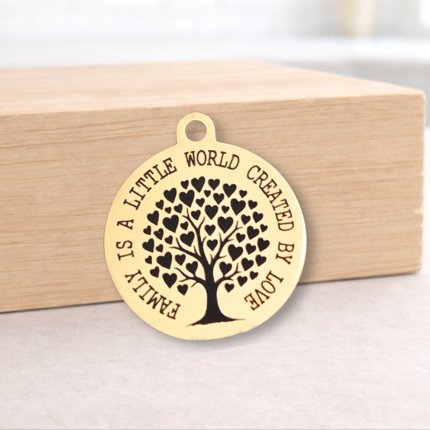 Gold pendant with tree of hearts design and engraved text on a wooden block.