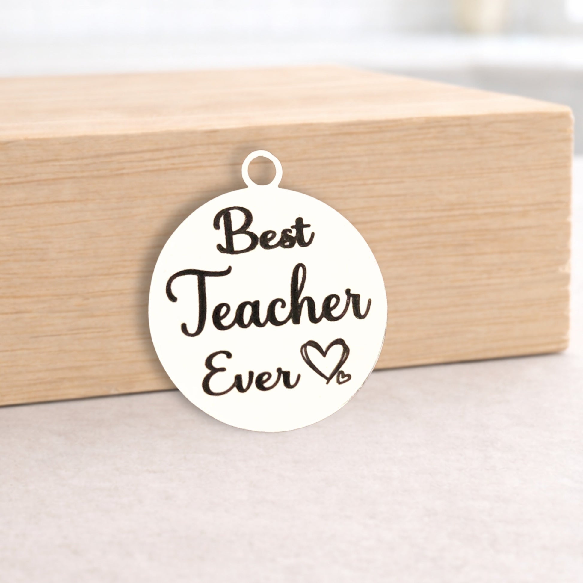 Round pendant with 'Best Teacher Ever' text on a wooden block